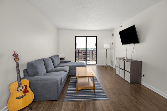 living room with a textured ceiling, wood finished floors, visible vents, and baseboards
