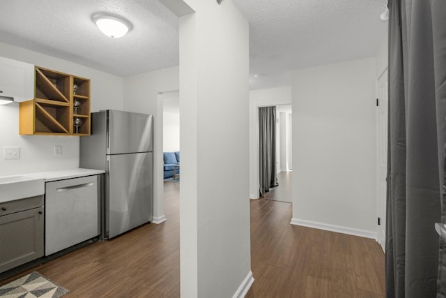 kitchen with open shelves, a textured ceiling, light countertops, dark wood finished floors, and appliances with stainless steel finishes