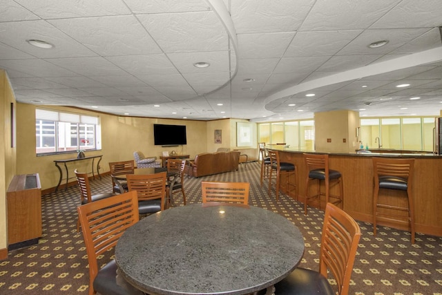 carpeted dining space with a wealth of natural light, a drop ceiling, and recessed lighting