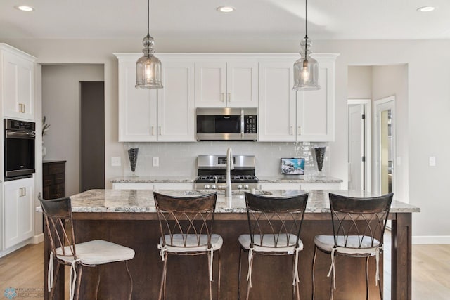 17917 Hayes Ave, Lakeville, MN 55044 - kitchen with light wood finished floors, stainless steel appliances, tasteful backsplash, white cabinetry, and decorative light fixtures