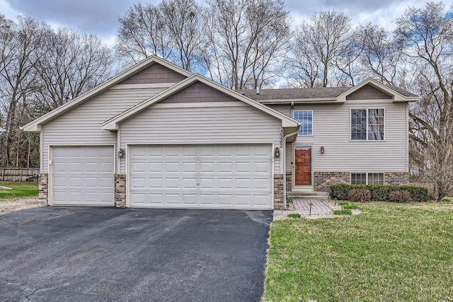 tri-level home with an attached garage, aphalt driveway, and brick siding