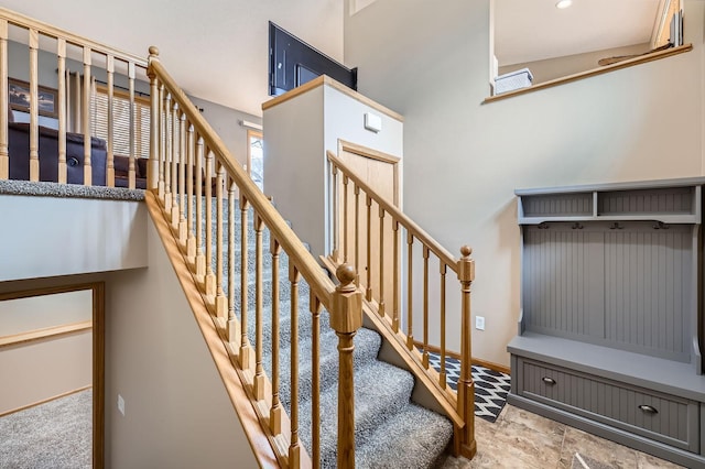 stairway featuring a towering ceiling and baseboards