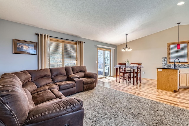living room featuring recessed lighting, an inviting chandelier, light wood-style flooring, vaulted ceiling, and a textured ceiling