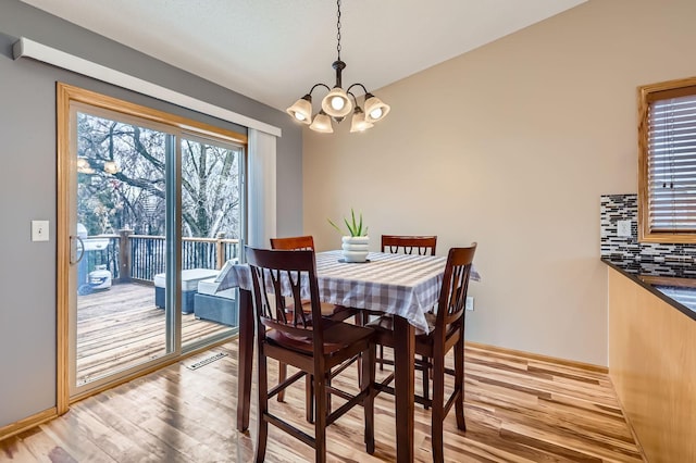 dining area with a chandelier, baseboards, and light wood-style floors