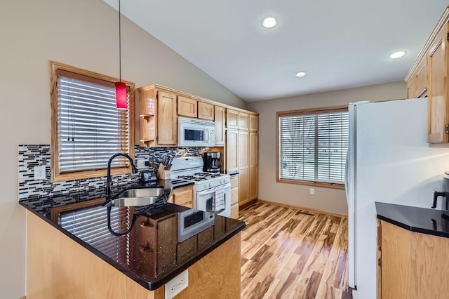 kitchen featuring lofted ceiling, a sink, light wood-style floors, light brown cabinetry, and white appliances