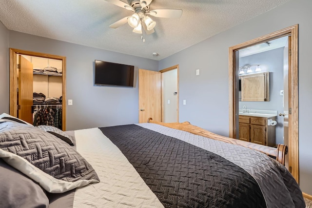 bedroom with a closet, a ceiling fan, a spacious closet, a textured ceiling, and ensuite bathroom