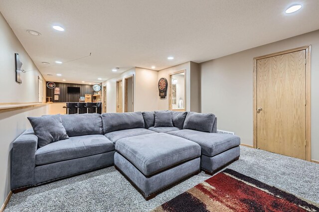 carpeted living room with recessed lighting, bar, and baseboards