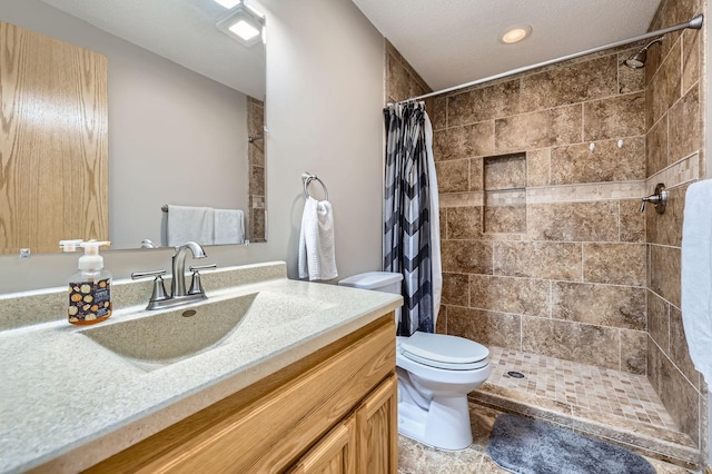 full bath with toilet, tiled shower, and vanity