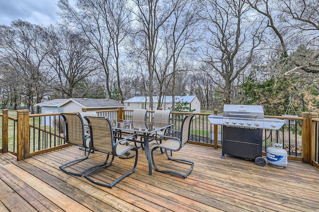 wooden deck with area for grilling, outdoor dining area, and an outdoor structure