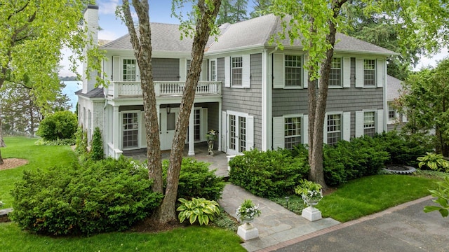 547 Harrington Rd, Wayzata, MN 55391 - view of front of property with french doors, a chimney, roof with shingles, a balcony, and a front lawn