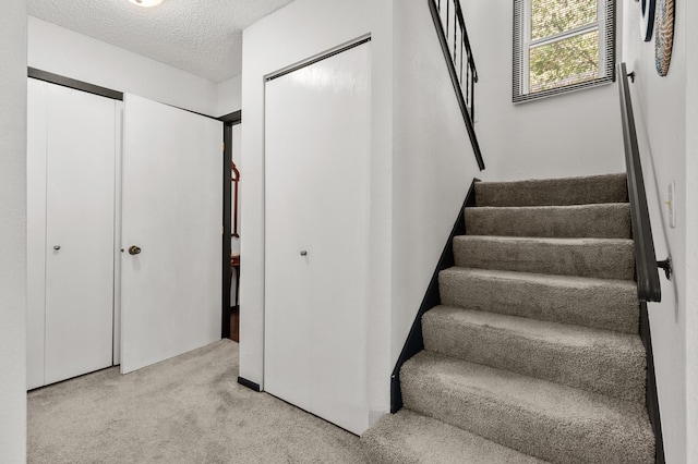 stairway featuring carpet flooring and a textured ceiling