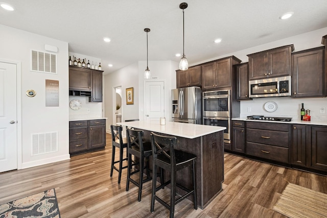12985 Legacy Creek Pkwy NE, Blaine, MN 55449 - kitchen featuring stainless steel appliances, wood finished floors, dark brown cabinets, light countertops, and recessed lighting