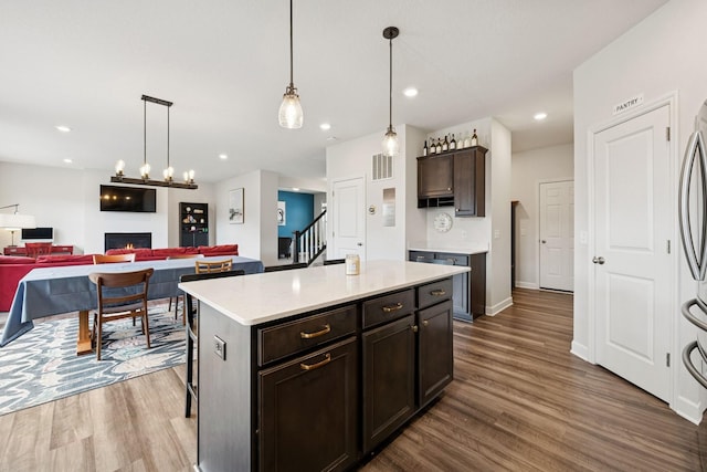 12985 Legacy Creek Pkwy NE, Blaine, MN 55449 - kitchen featuring a warm lit fireplace, dark wood finished floors, light countertops, open floor plan, and recessed lighting