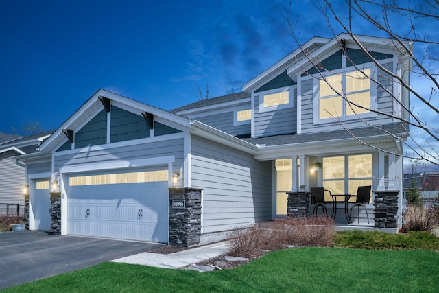 12985 Legacy Creek Pkwy NE, Blaine, MN 55449 - craftsman-style home featuring covered porch, stone siding, a garage, driveway, and roof with shingles