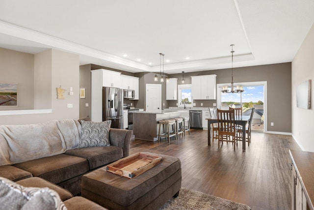 1302 Windrush Rd, Buffalo, MN 55313 - living area featuring a tray ceiling, dark wood-style floors, a chandelier, recessed lighting, and baseboards