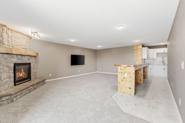 1302 Windrush Rd, Buffalo, MN 55313 - unfurnished living room featuring baseboards, a fireplace, a sink, and light colored carpet