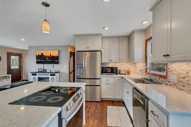 kitchen featuring dark wood-style floors, a sink, appliances with stainless steel finishes, backsplash, and decorative light fixtures