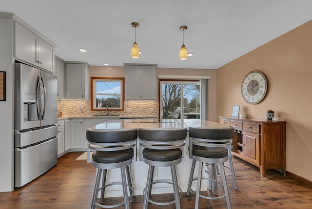 kitchen with stainless steel fridge, tasteful backsplash, dark wood finished floors, and a healthy amount of sunlight