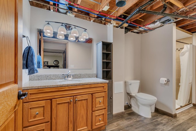 bathroom with a shower with curtain, wood finished floors, baseboards, vanity, and toilet