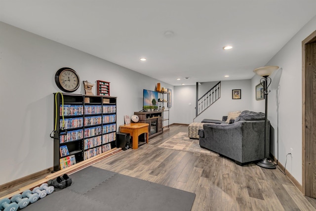 living area with recessed lighting, baseboards, stairs, and wood finished floors