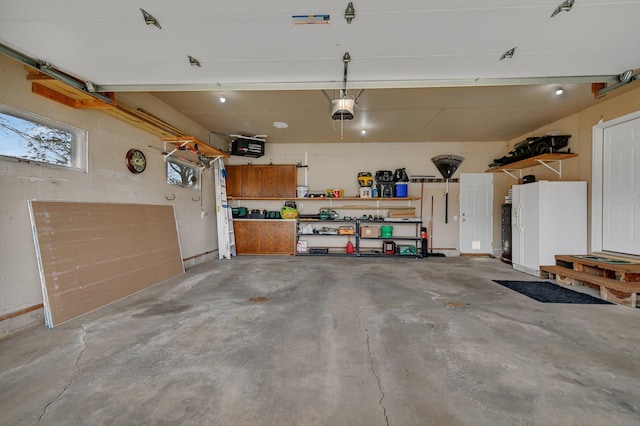 garage featuring a workshop area, white refrigerator with ice dispenser, and a garage door opener