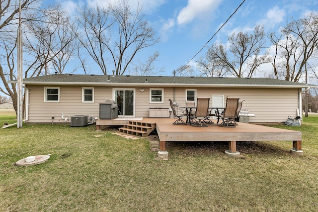 rear view of property featuring central air condition unit, outdoor dining area, a lawn, and a wooden deck
