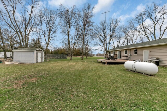 view of yard with fence, an outbuilding, a wooden deck, and a shed
