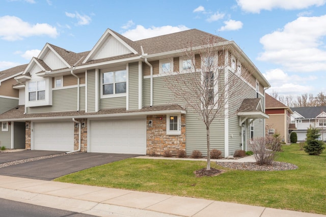 multi unit property featuring an attached garage, driveway, a front lawn, and stone siding