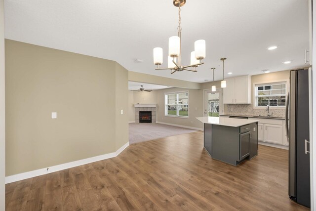 kitchen featuring a kitchen island, baseboards, white cabinets, freestanding refrigerator, and open floor plan