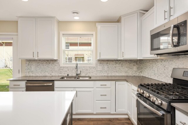 kitchen featuring a sink, white cabinetry, backsplash, and stainless steel appliances