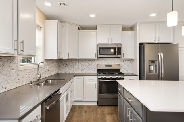 kitchen with stainless steel appliances, dark wood finished floors, white cabinetry, and a sink