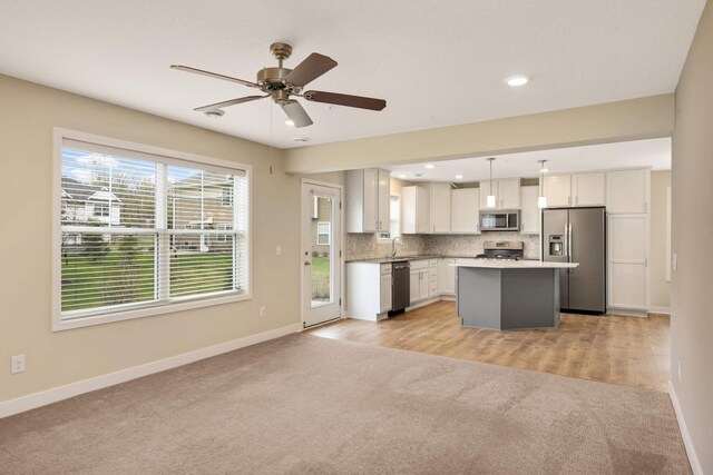 kitchen featuring a sink, baseboards, open floor plan, light carpet, and stainless steel appliances