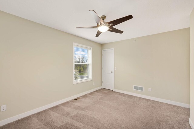 empty room featuring a ceiling fan, baseboards, visible vents, and light carpet