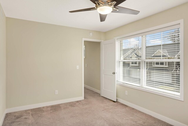 empty room with a ceiling fan, baseboards, and light carpet