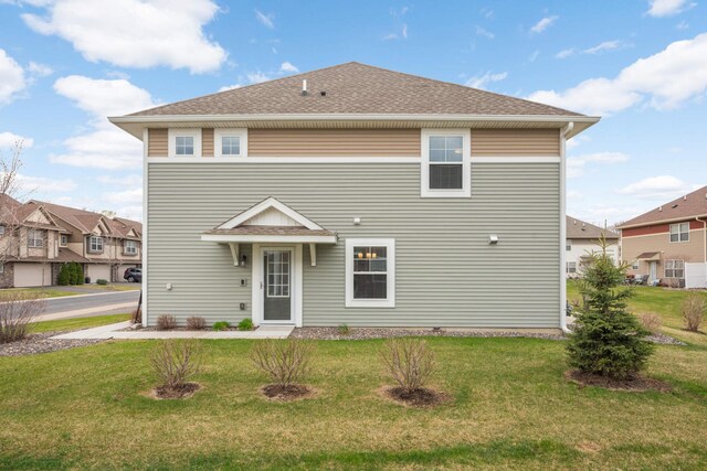 view of front of property with a front lawn, roof with shingles, and a residential view
