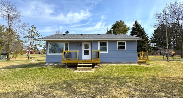 bungalow-style home with roof with shingles, a front lawn, and a deck