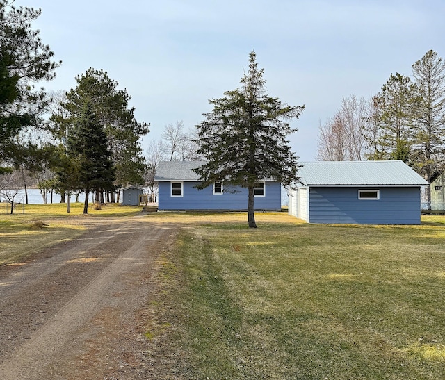 single story home featuring a front lawn, driveway, and an outbuilding