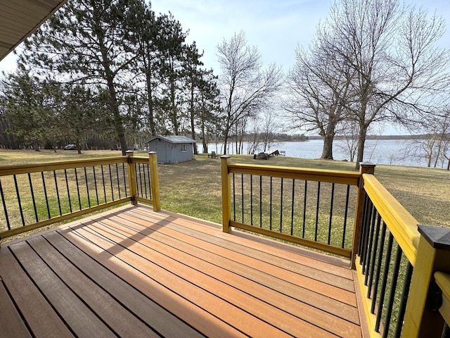 deck with a lawn, a water view, and an outbuilding