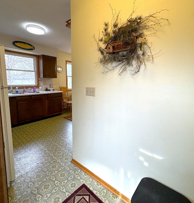 corridor with light floors, baseboards, and a sink