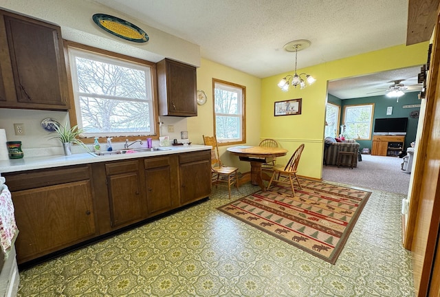 kitchen featuring light countertops, a sink, a textured ceiling, and a healthy amount of sunlight