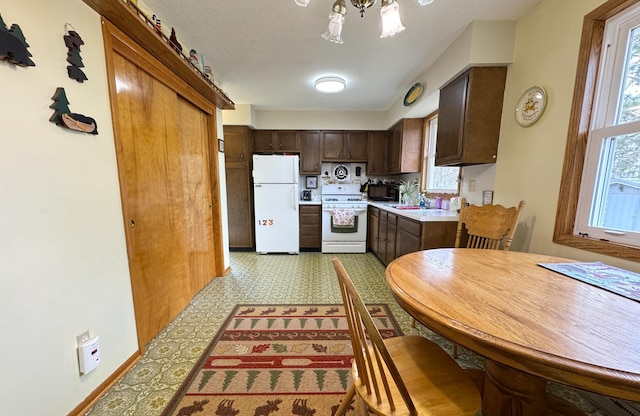 kitchen featuring a sink, white appliances, light floors, dark brown cabinetry, and light countertops