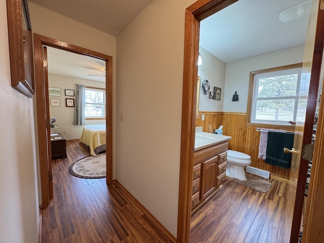 bathroom featuring toilet, a wainscoted wall, wood finished floors, and a textured ceiling