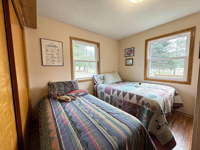 bedroom featuring wood finished floors, a textured ceiling, and multiple windows
