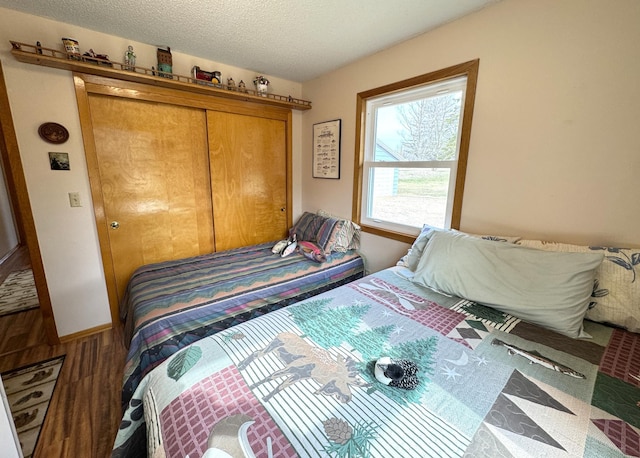 bedroom with wood finished floors, a textured ceiling, and a closet