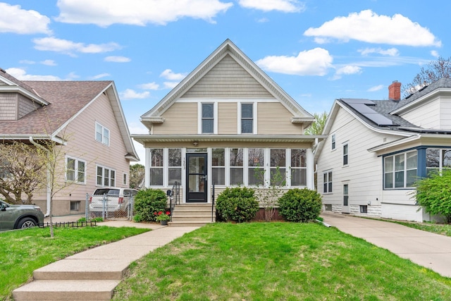 bungalow-style house featuring a sunroom, a gate, fence, and a front yard