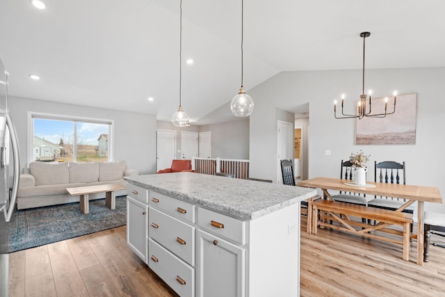 907 7th Ave, Wanamingo, MN 55983 - kitchen featuring light wood finished floors, open floor plan, a chandelier, a kitchen island, and lofted ceiling