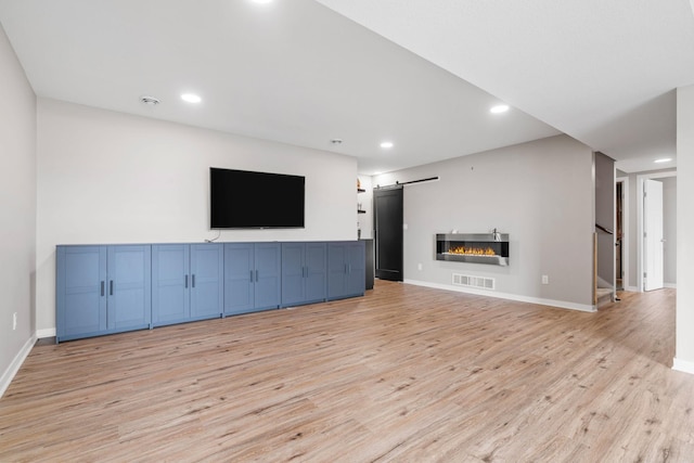 907 7th Ave, Wanamingo, MN 55983 - unfurnished living room with light wood-style floors, recessed lighting, baseboards, and a barn door