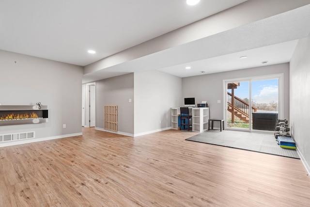 907 7th Ave, Wanamingo, MN 55983 - unfurnished living room featuring wood finished floors, a warm lit fireplace, baseboards, and recessed lighting