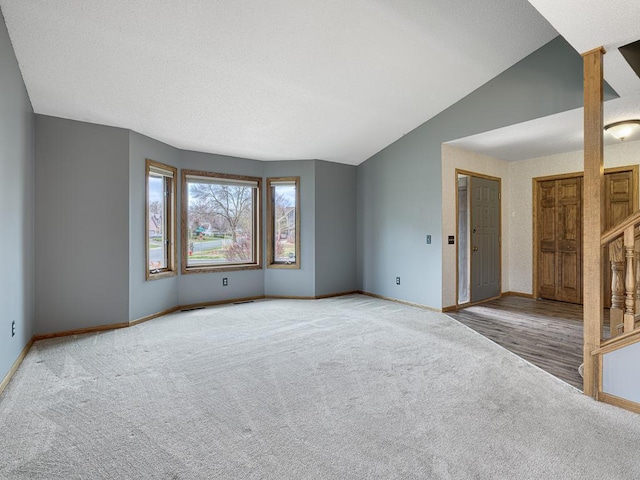 carpeted spare room featuring lofted ceiling, visible vents, and baseboards