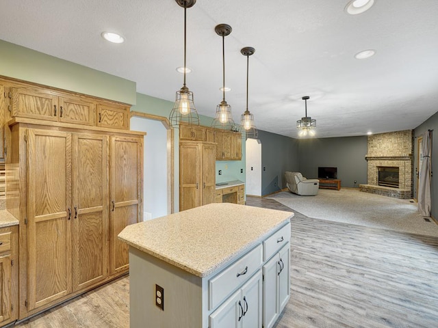 kitchen featuring recessed lighting, light wood-type flooring, a kitchen island, pendant lighting, and a brick fireplace